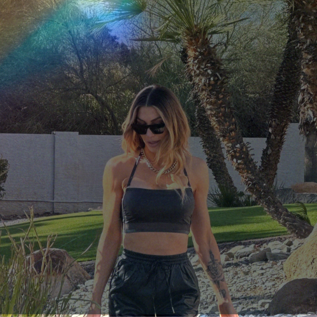 Woman walking outdoors with palm trees and a rainbow in the sky